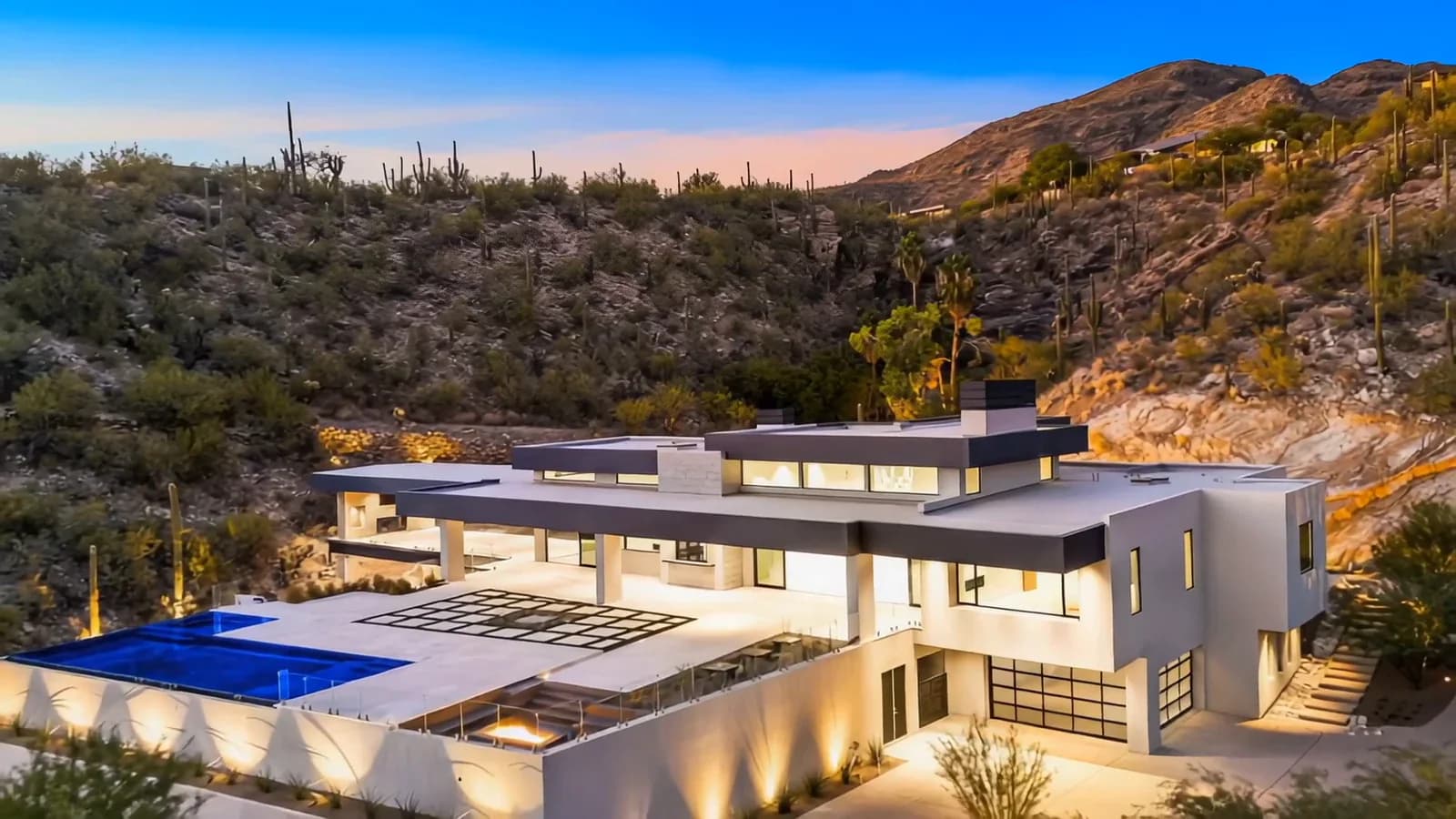 Cinematic aerial view of a modern desert property at twilight